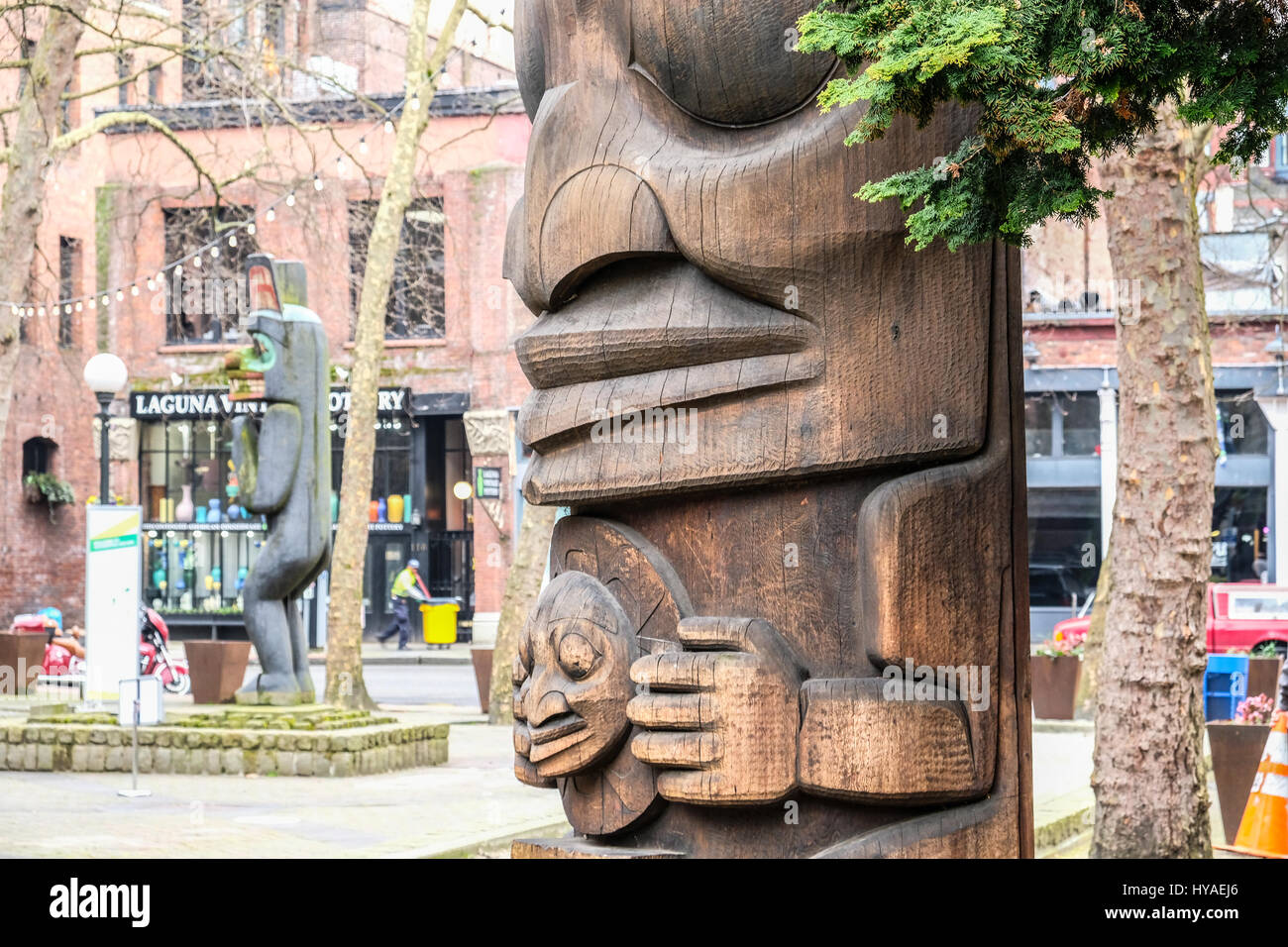 Two Northwest native American totem poles in Seattle's Pioneer Square.  Nearly empty street.  Horizontal image. Stock Photo