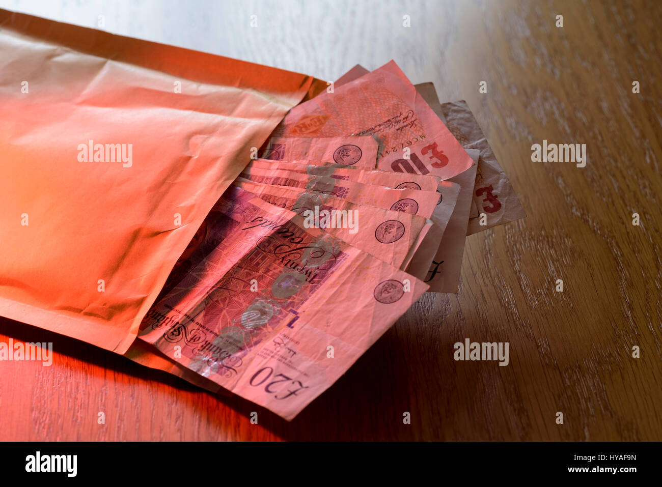 Brown envelope stuffed full of cash. Pay off or bribe with a bundle of cash. Stock Photo
