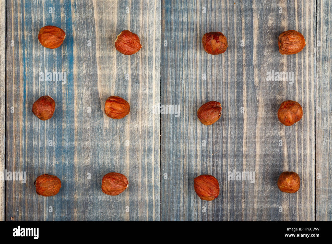 Twelve hazelnut nuts without a shell are arranged in three rows on a wooden background Stock Photo