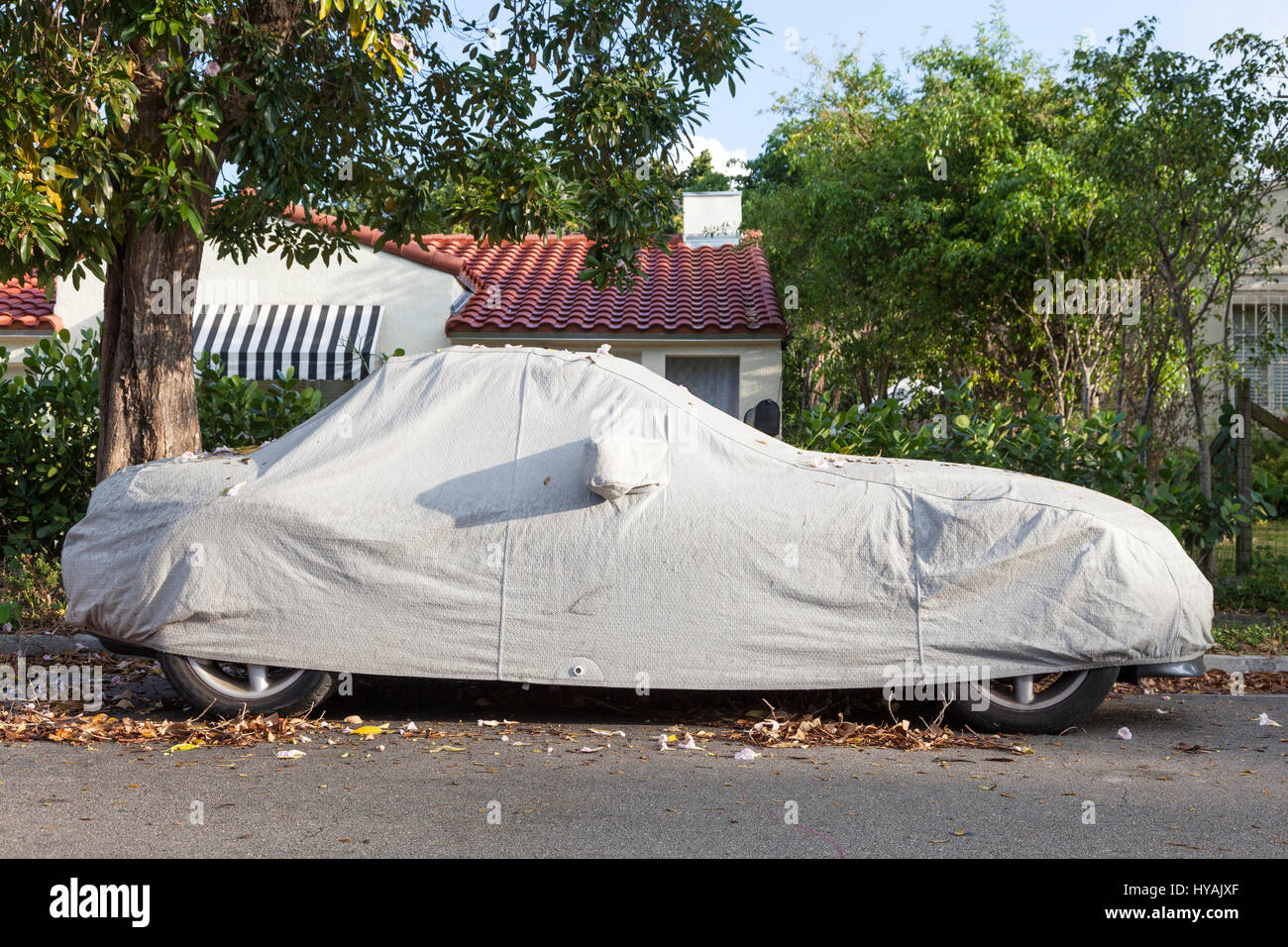 Car under a protective cover parked on the roadside in the city Stock Photo