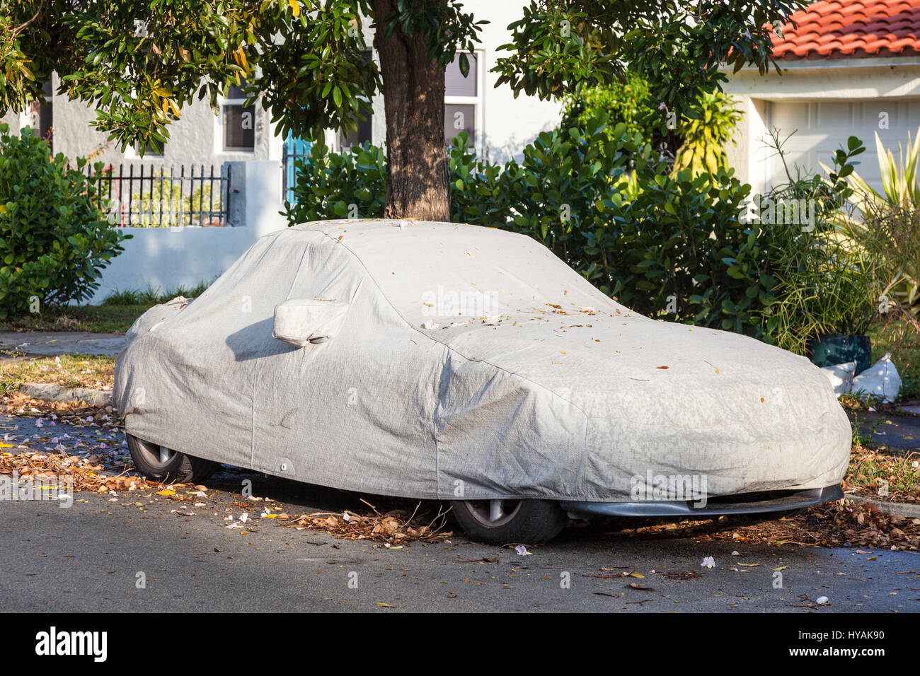 Car under a protective cover parked on the roadside in the city Stock Photo