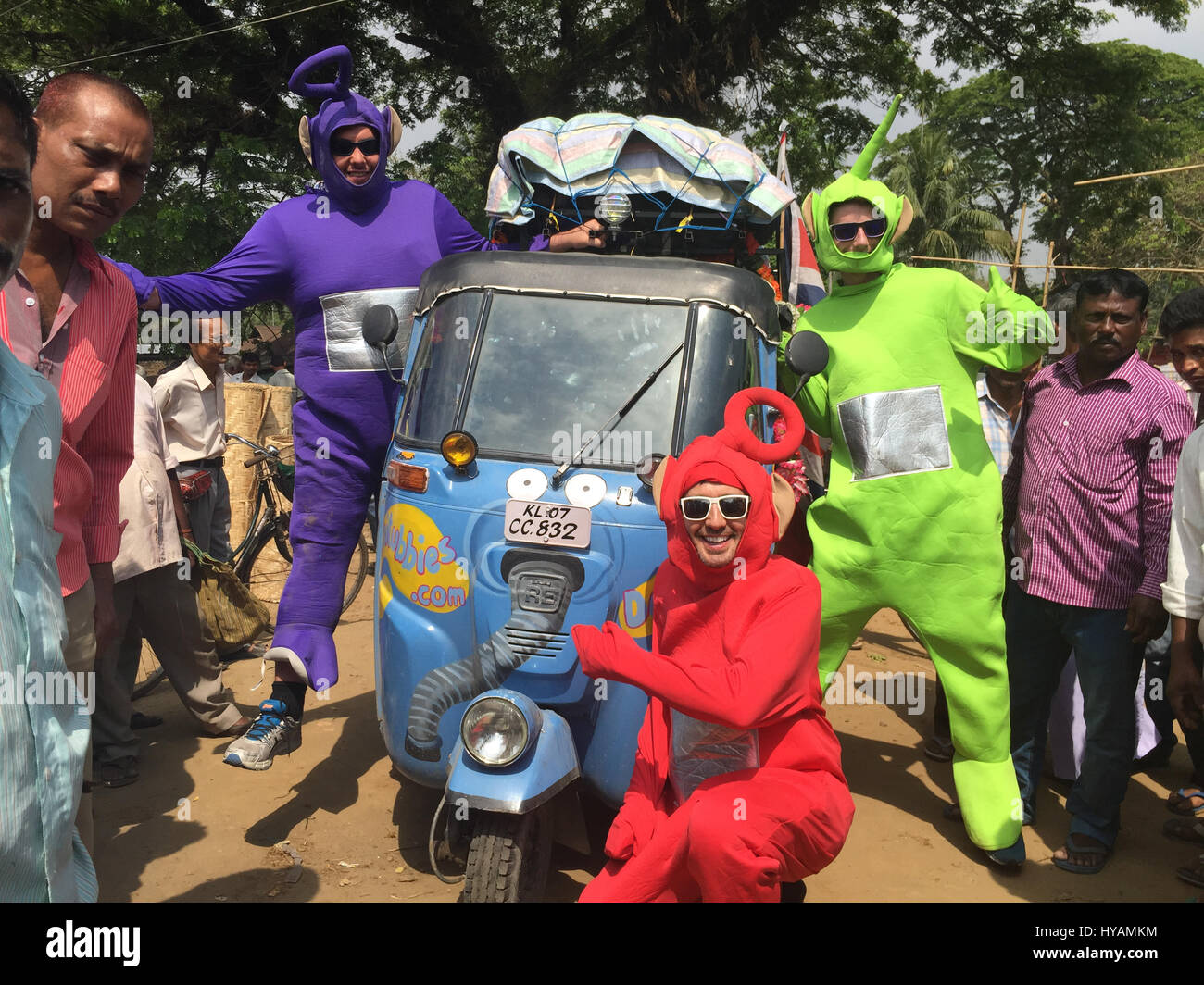 Phillip Miller (left), Sean Miller (middle) Tyler Newman (right) are surrounded by curious locals. THREE BRITONS are saying E-OH to the Subcontinent by taking on the eccentric challenge of crossing India on a rickshaw dressed as the iconic children’s television characters the Teletubbies. Driving 2,000miles on pothole infested dirt roads from the “Golden City” of Jaisalmer in the state of Rajastan to the station of Shillong in the Himalayas pictures show how locals responded to the wacky-costumed trio who hope to raise £30K for a women’s refuge in Bangladesh. Led by estate agent Sean Newman (4 Stock Photo