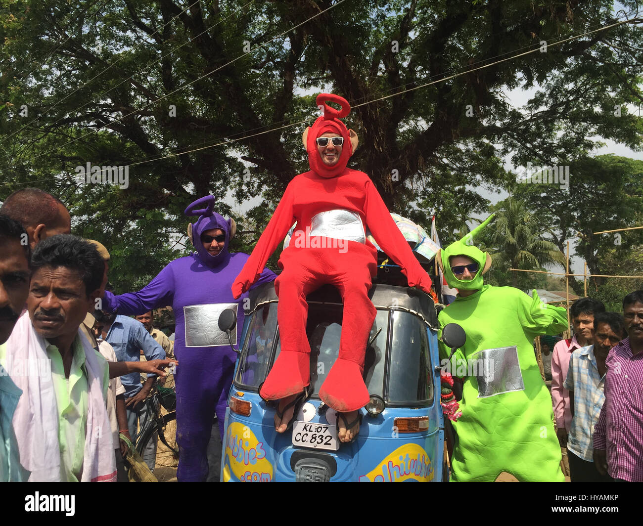 Phillip Miller (left), Sean Miller (middle) Tyler Newman (right) are surrounded by curious locals. THREE BRITONS are saying E-OH to the Subcontinent by taking on the eccentric challenge of crossing India on a rickshaw dressed as the iconic children’s television characters the Teletubbies. Driving 2,000miles on pothole infested dirt roads from the “Golden City” of Jaisalmer in the state of Rajastan to the station of Shillong in the Himalayas pictures show how locals responded to the wacky-costumed trio who hope to raise £30K for a women’s refuge in Bangladesh. Led by estate agent Sean Newman (4 Stock Photo