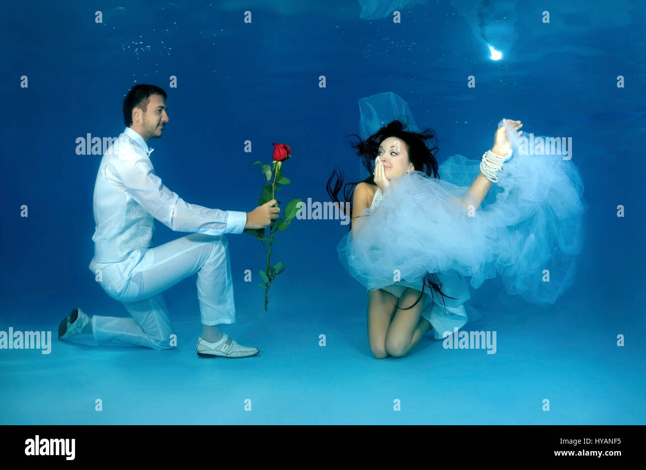 ALL ROUND EXCLUSIVE. ODESSA, UKRAINE: Bride and groom pose for underwater snap showing their courtship. NEWLYWEDS are literally taking the plunge when it comes to commemorating their new marriage. Jumping in at the deep end, these quirky images tell the story of the relationship between DJ Natalia Kol (26) and Designer Viacheslav Kol (28) from Odessa, Ukraine, from courtship to marriage – while three-feet underwater.  Pictures show how the groom wins over the bride with a red rose and goes down on one knee for the big proposal. We can also see the make-up artist going to work on the big day, a Stock Photo
