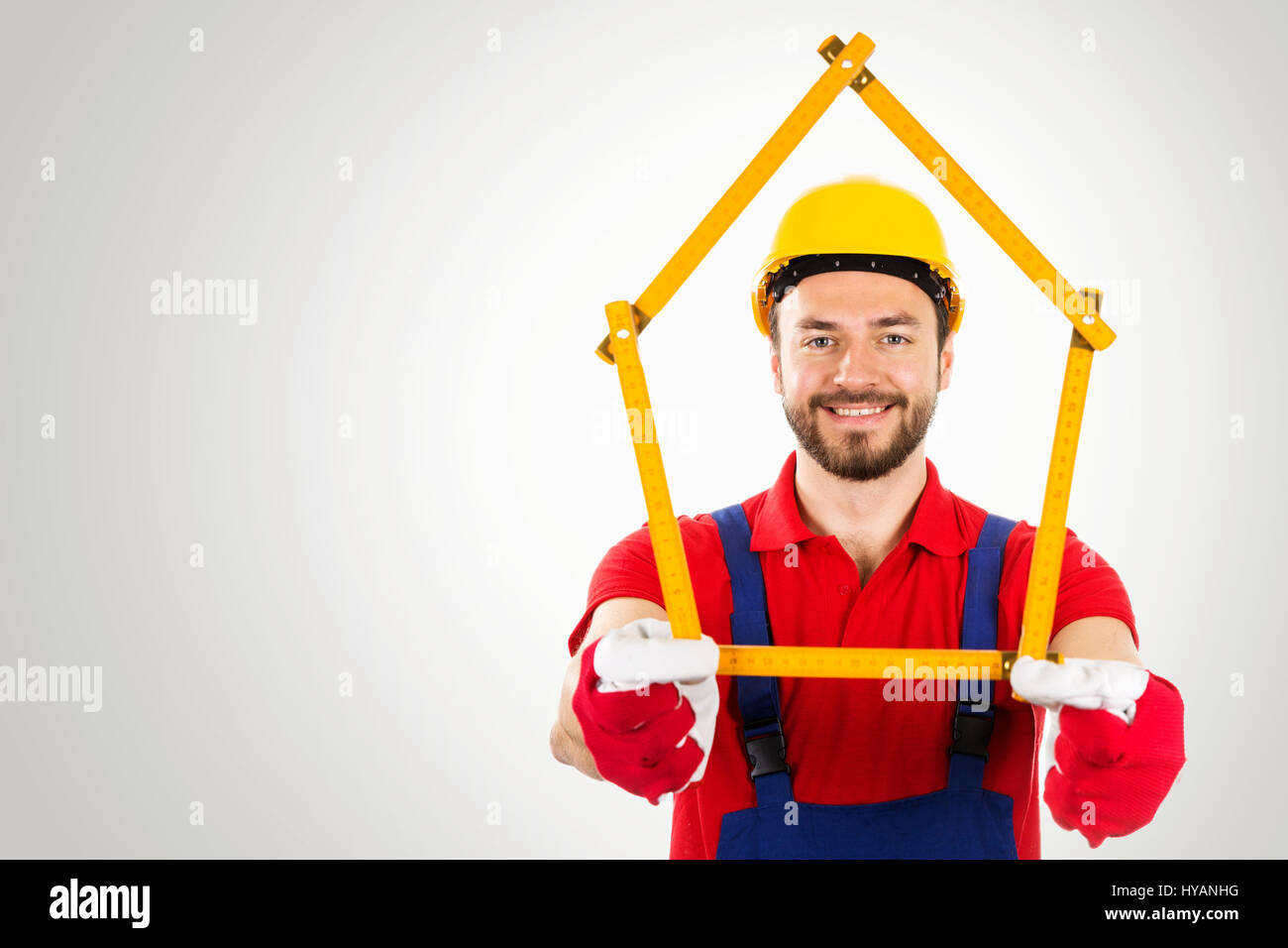 home improvement - handyman with house shaped ruler in hands on gray background with copy space Stock Photo