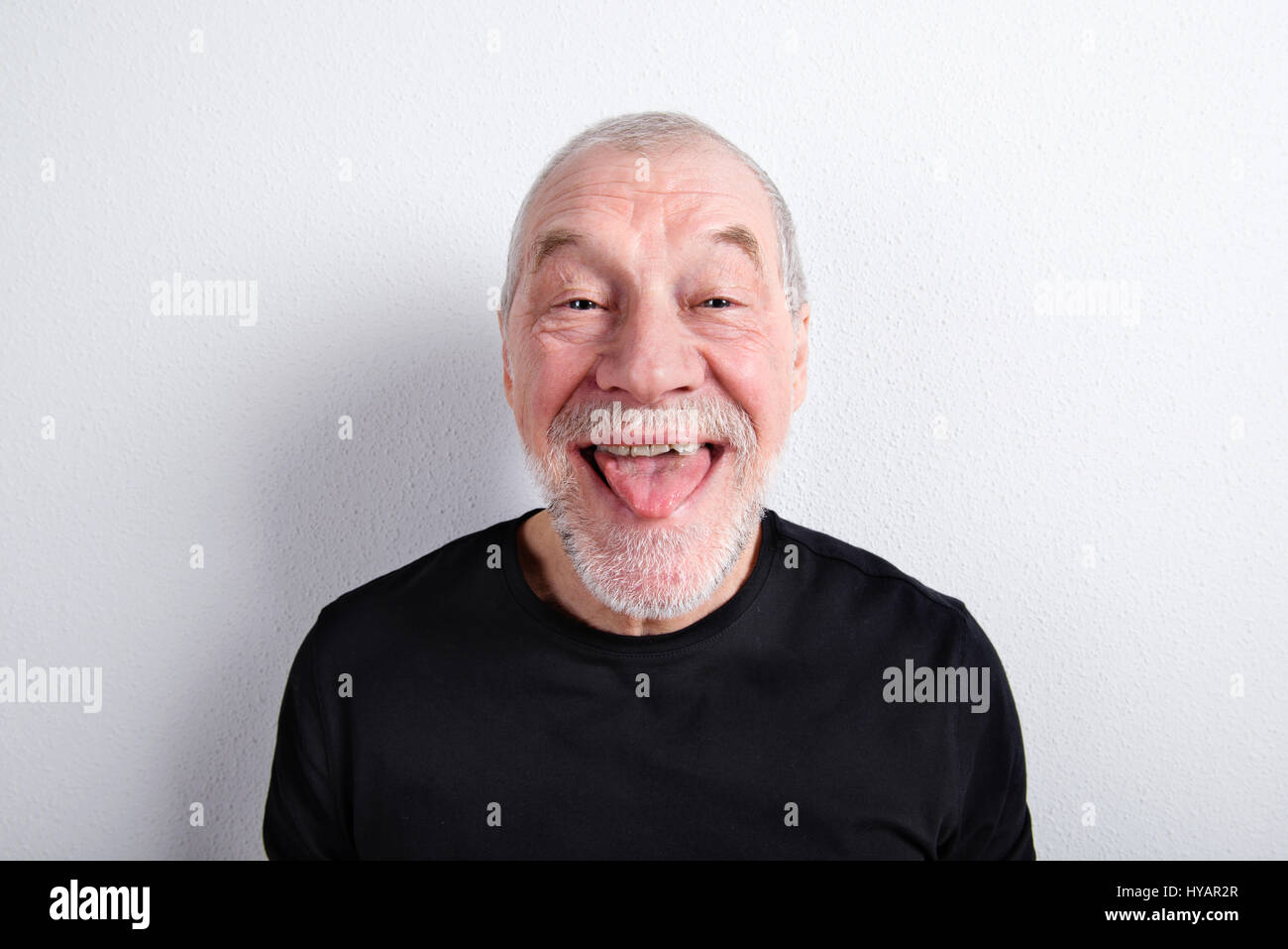 Senior man making funny face, sticking tongue out, studio shot. Stock Photo