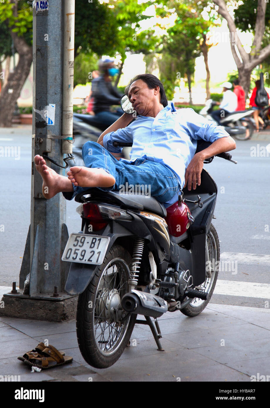 Some people can sleep anywhere even on a motor bike in Saigon Stock Photo