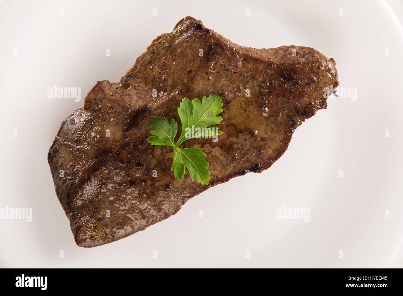 High angle view of a veal liver steack on a white plate Stock Photo