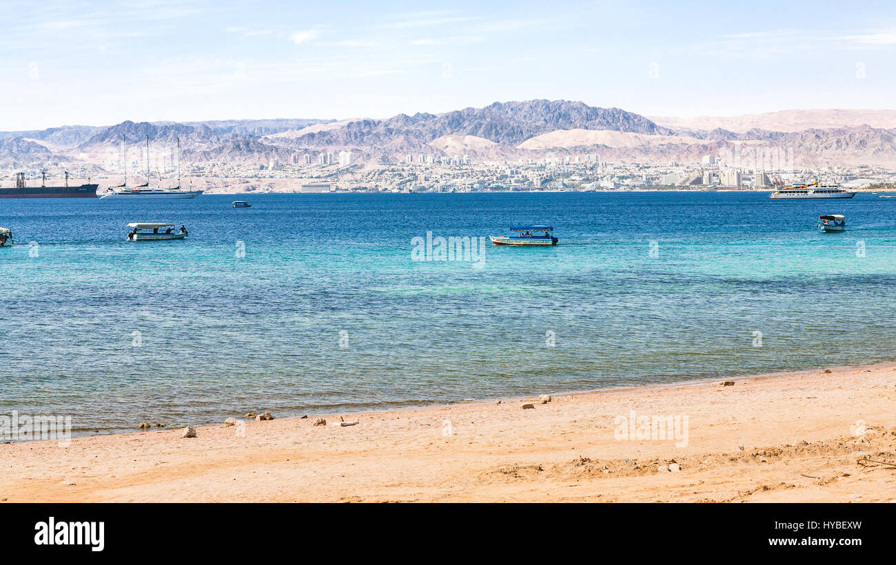 AQABA, JORDAN - FEBRUARY 23, 2012: urban beach of Aqaba and view of Eilat city in the background in winter. Jordan country has only one exit to sea in Stock Photo