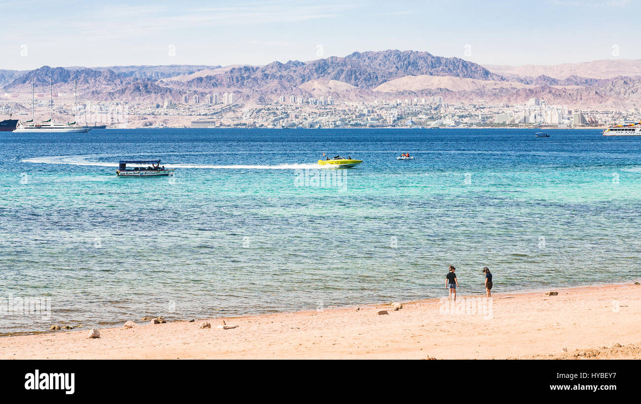 AQABA, JORDAN - FEBRUARY 23, 2012: sand beach of Aqaba city and view of Eilat city in background in winter. Jordan country has only one exit to sea in Stock Photo