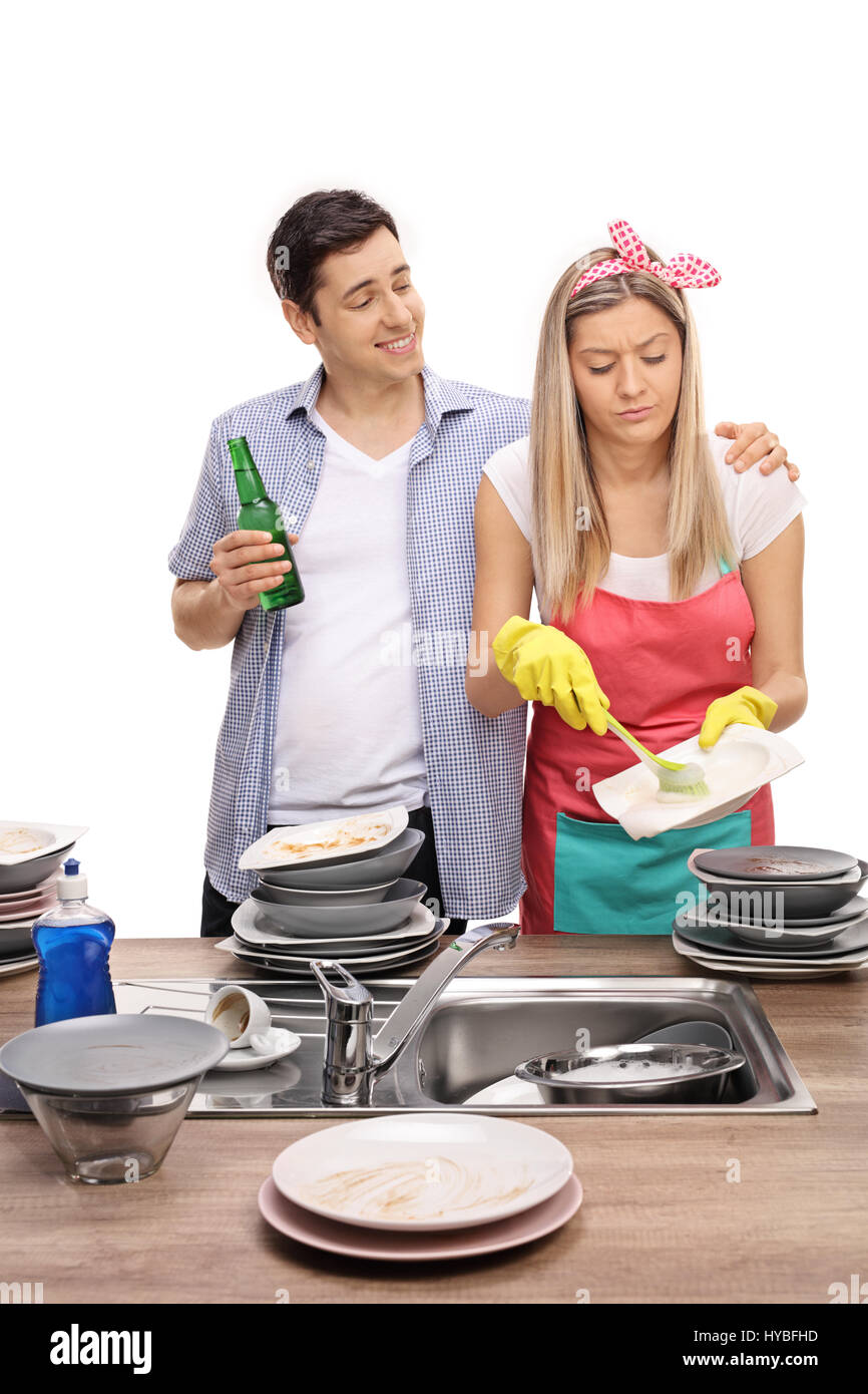 Young man with a beer bottle hugging his wife while she is doing the dishes isolated on white background Stock Photo