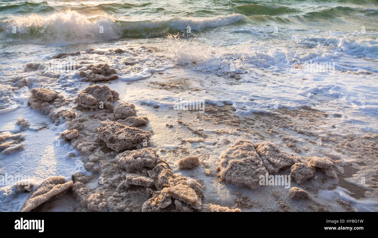 Travel to Middle East country Kingdom of Jordan - crystalline salt on shore of Dead Sea on winter sunset Stock Photo