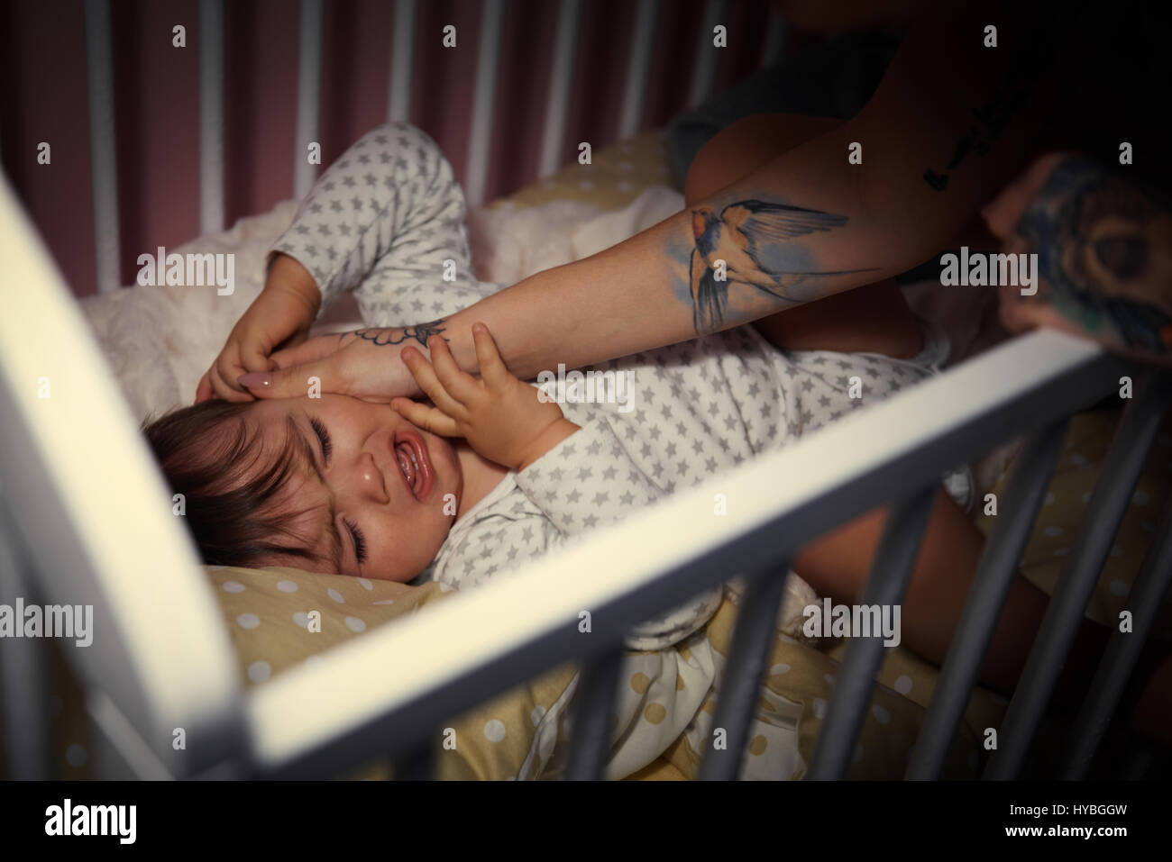 Crying baby boy in a crib Stock Photo