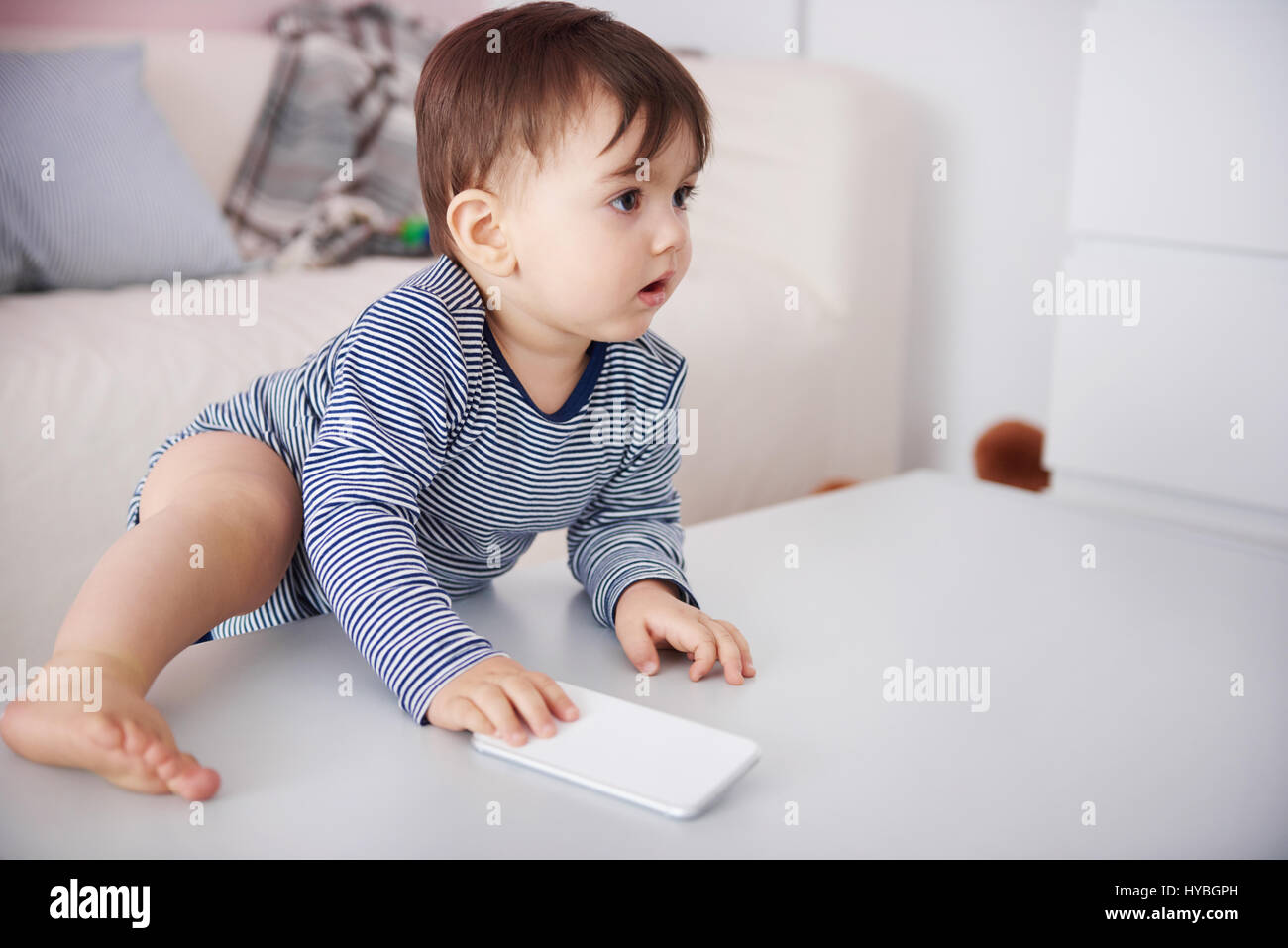 Little baby climbing with cell phone on the table Stock Photo Alamy