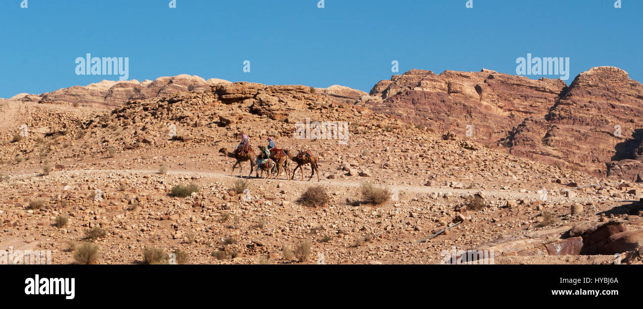 Jordan, Middle East: Bedouins and camels in the desert landscape of the archaeological Nabataean city of Petra Stock Photo