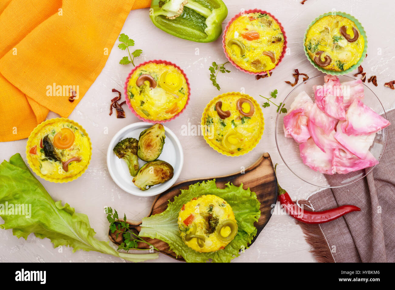 Omelette with colored pasta, mushrooms, vegetables and herbs, cooked in the form of mafins. The top view. Breakfast. Stock Photo