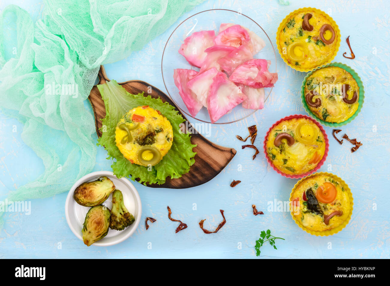 Omelette with colored pasta, mushrooms, vegetables and herbs, cooked in the form of mafins. The top view. Breakfast. Stock Photo