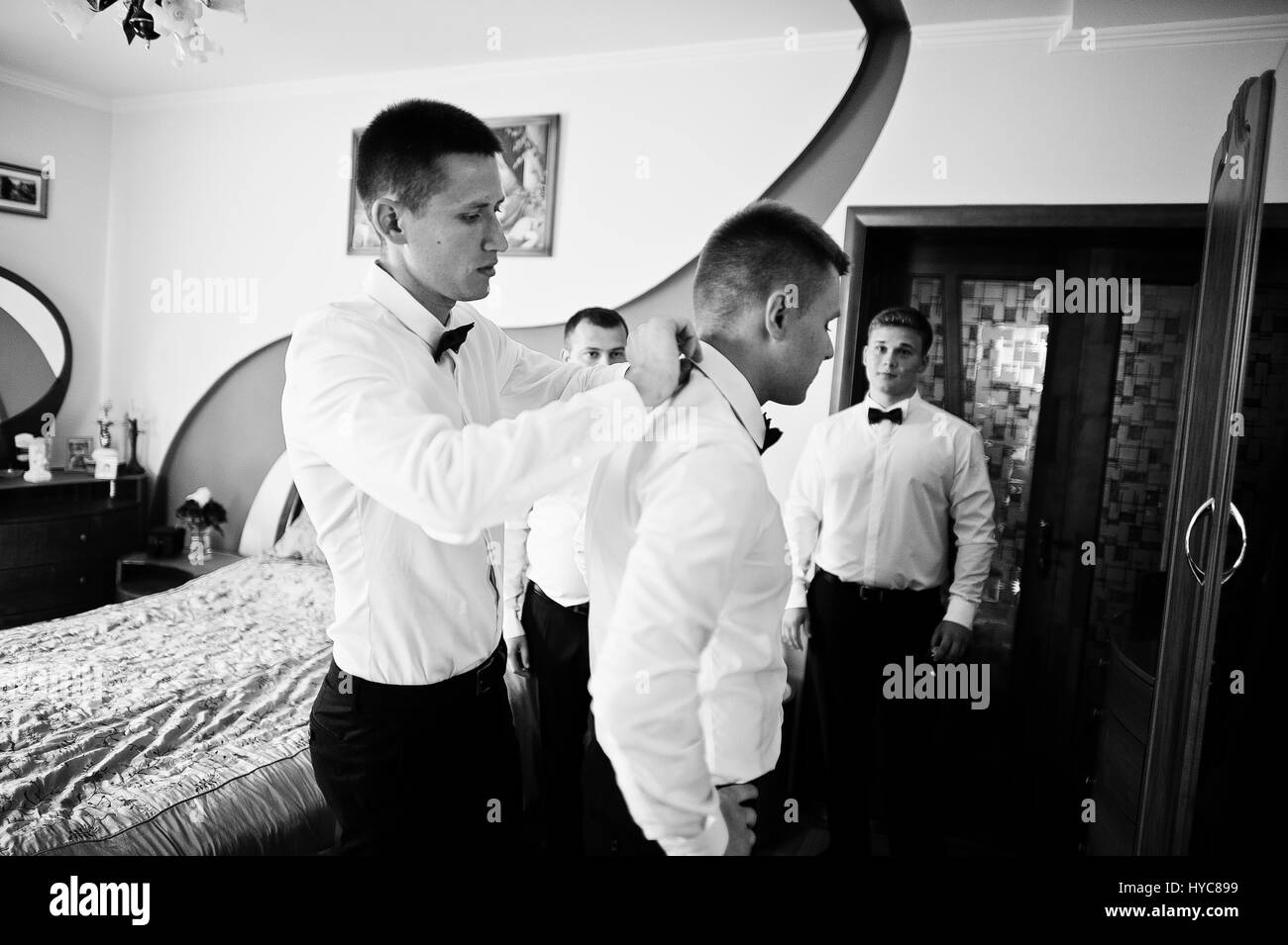Groom wears on his room at morning wedding with best mans Stock Photo