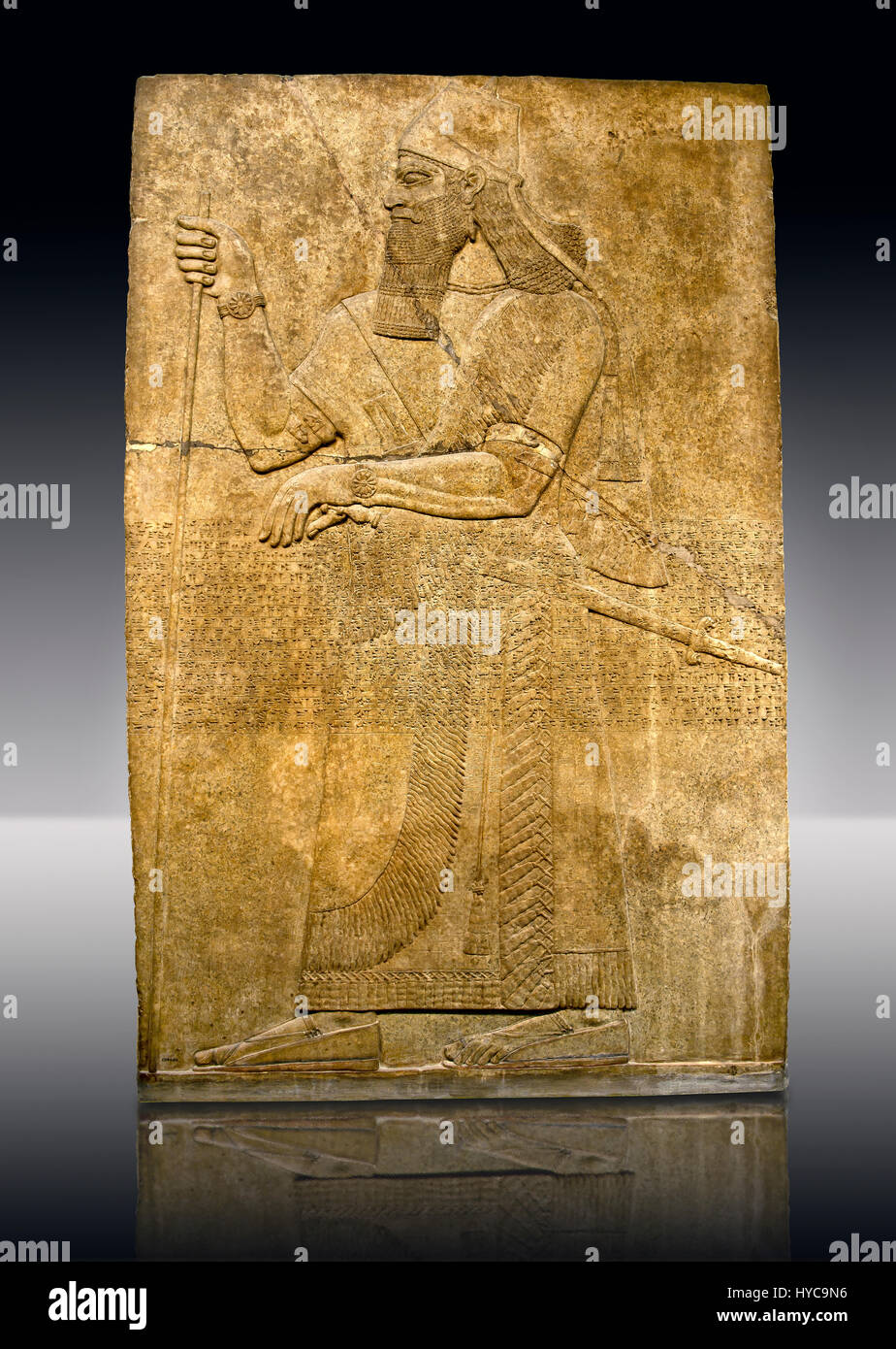 Assyrian relief sculpture panel  of King Ashurnaspiral II with his sword and a staff. The panel is possibly from his private apartments..  From Nimrud Stock Photo