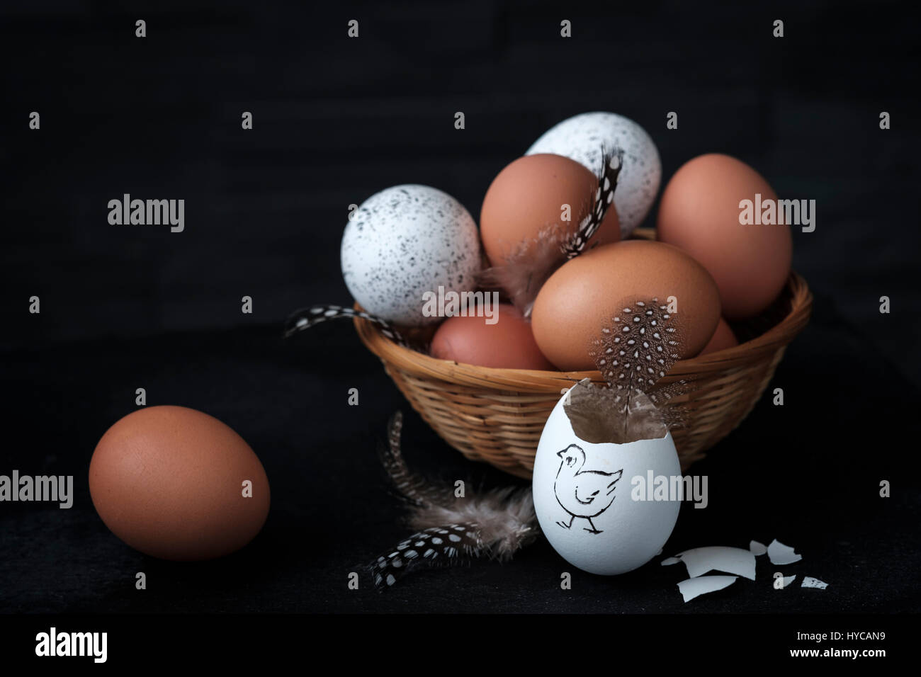 brown and white eggs in a wicker basket with a broken egg in the foreground Stock Photo