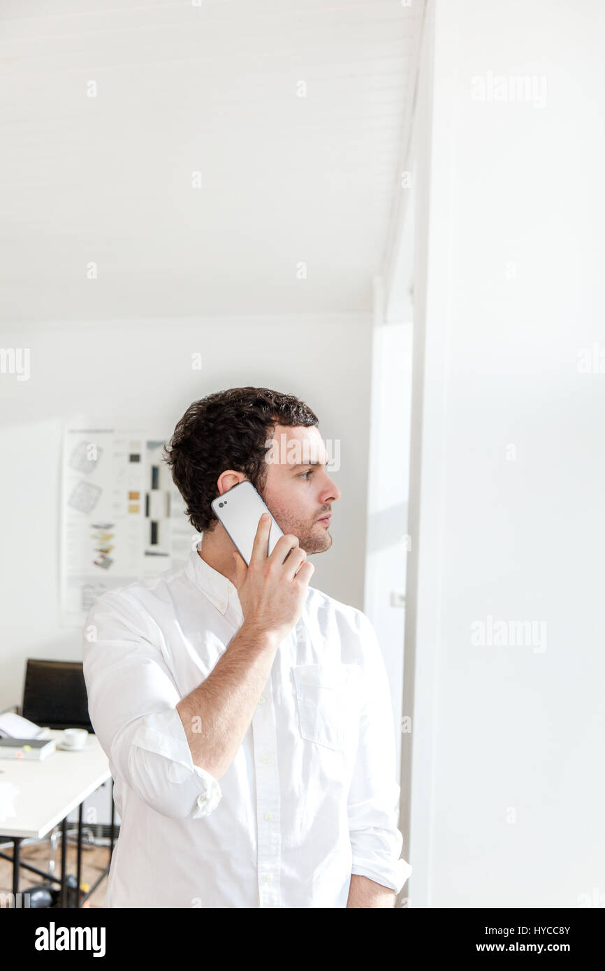 Mid adult man using smartphone to make telephone call looking away Stock Photo