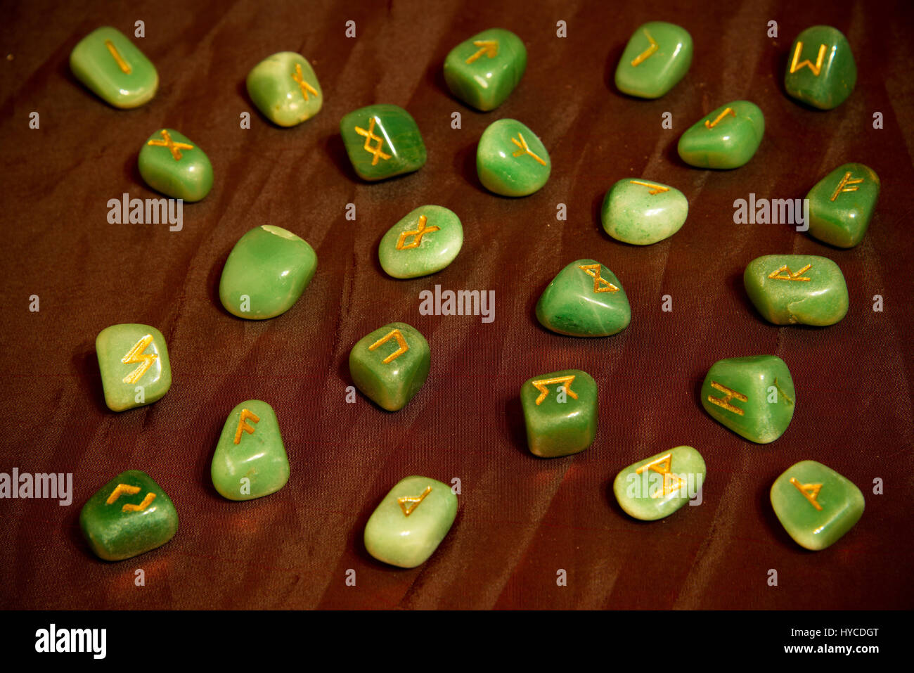 Green stone runes on the red background. Esoteric subjects. Stock Photo