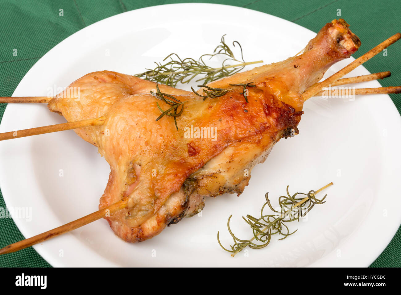 Homemade crispy baked rosemary chicken legs, on green background