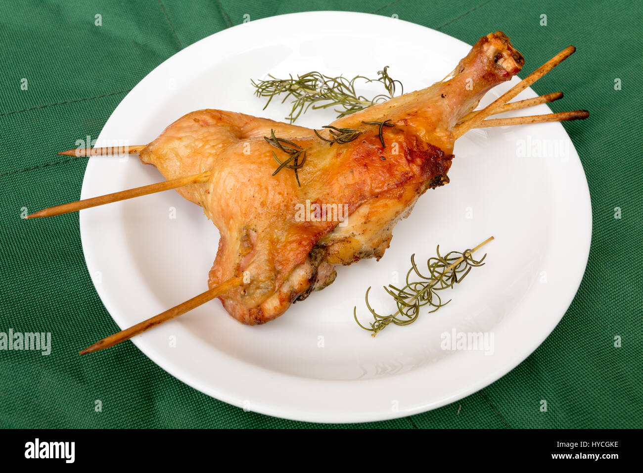 Homemade crispy baked rosemary chicken legs, on green background