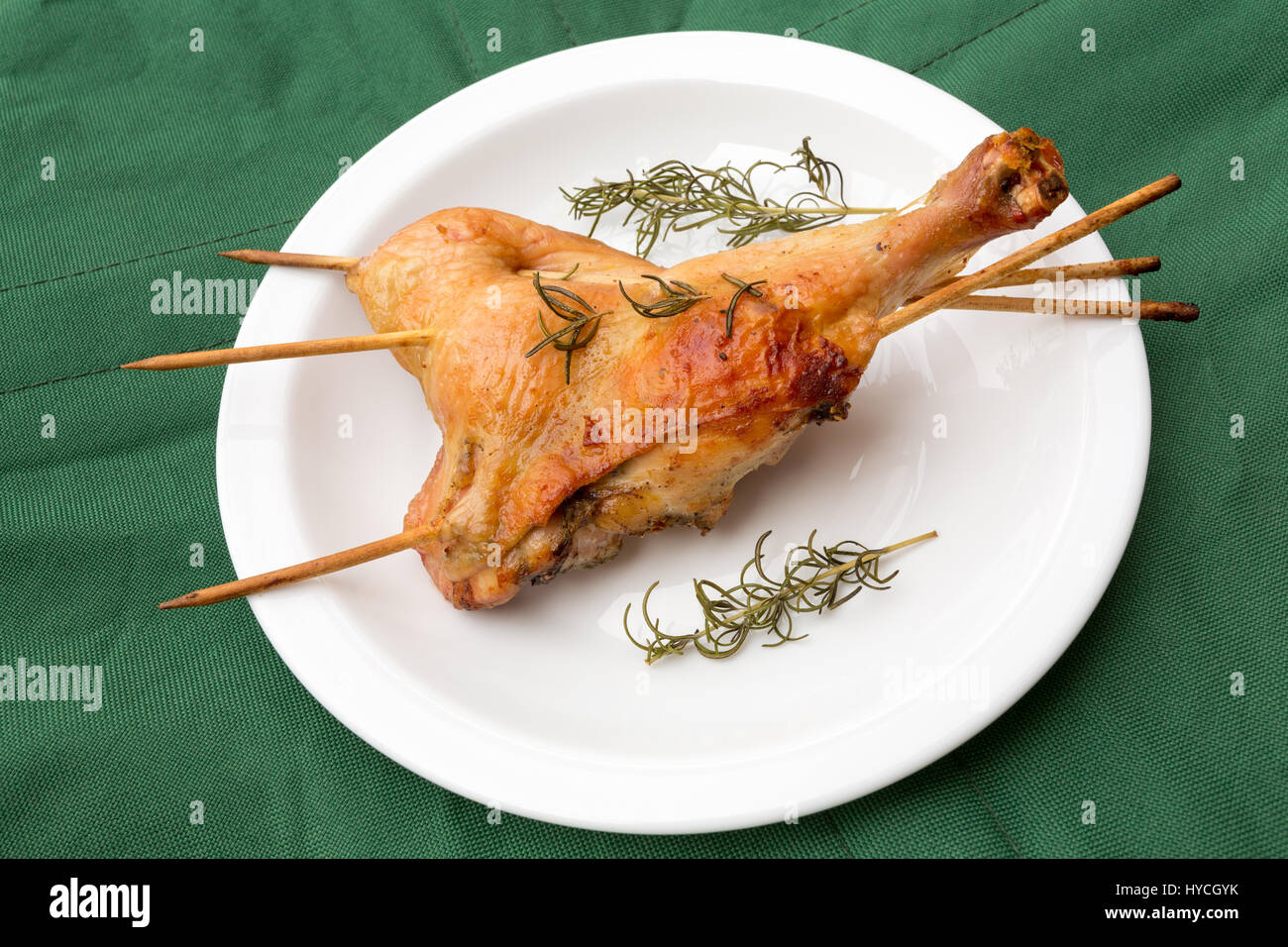 Homemade crispy baked rosemary chicken legs, on green background