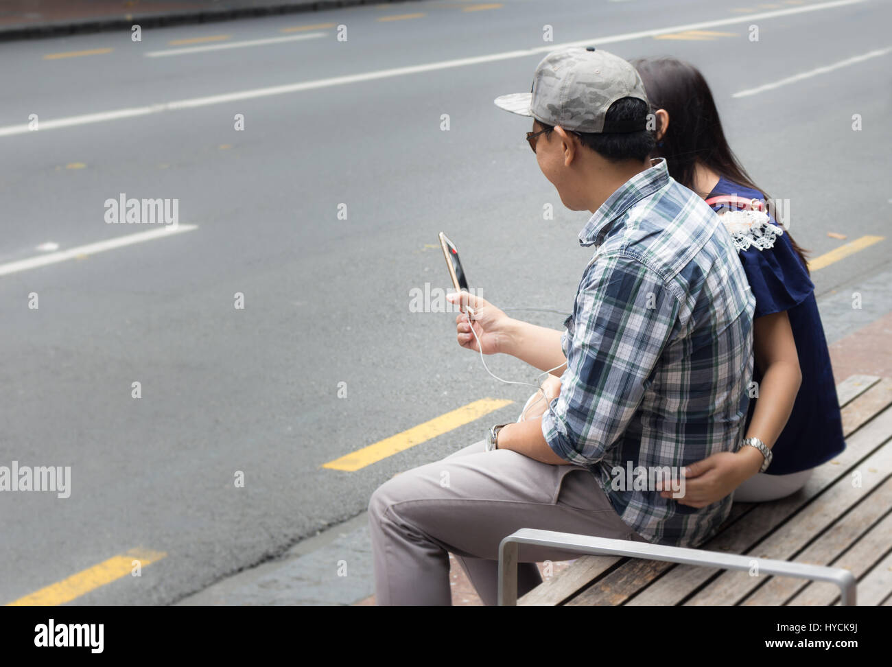 Auckland - February 17, 2017: Asian couple having a video chat sittiing at Queen Street in Auckland. Stock Photo
