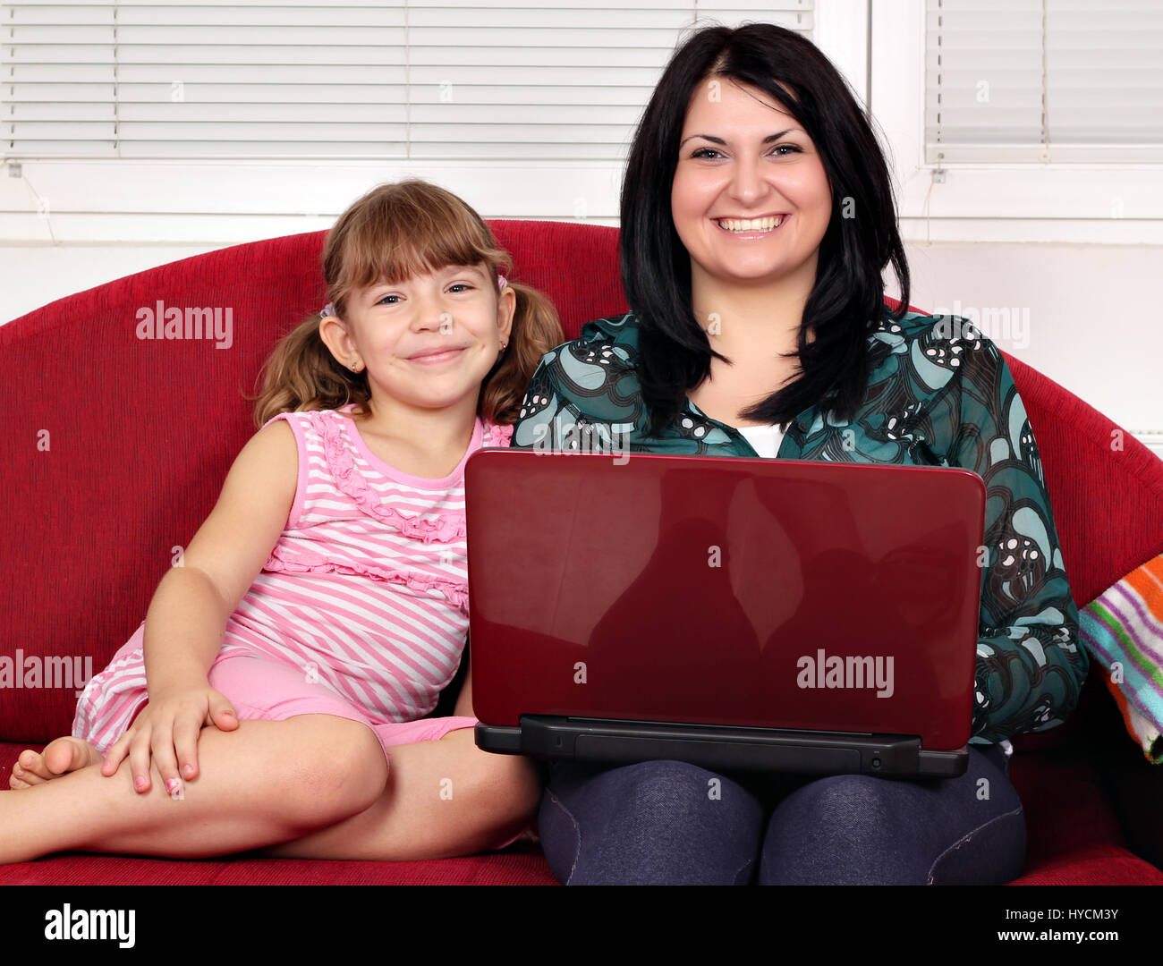 happy girls with laptop sitting on bed Stock Photo - Alamy