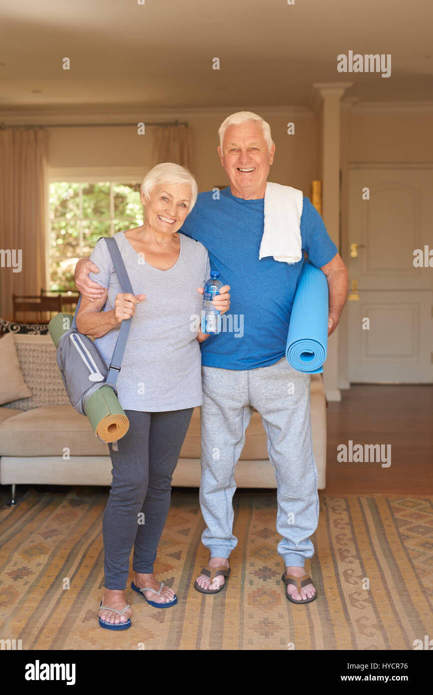 Active senior couple prepared for yoga standing together at home Stock Photo