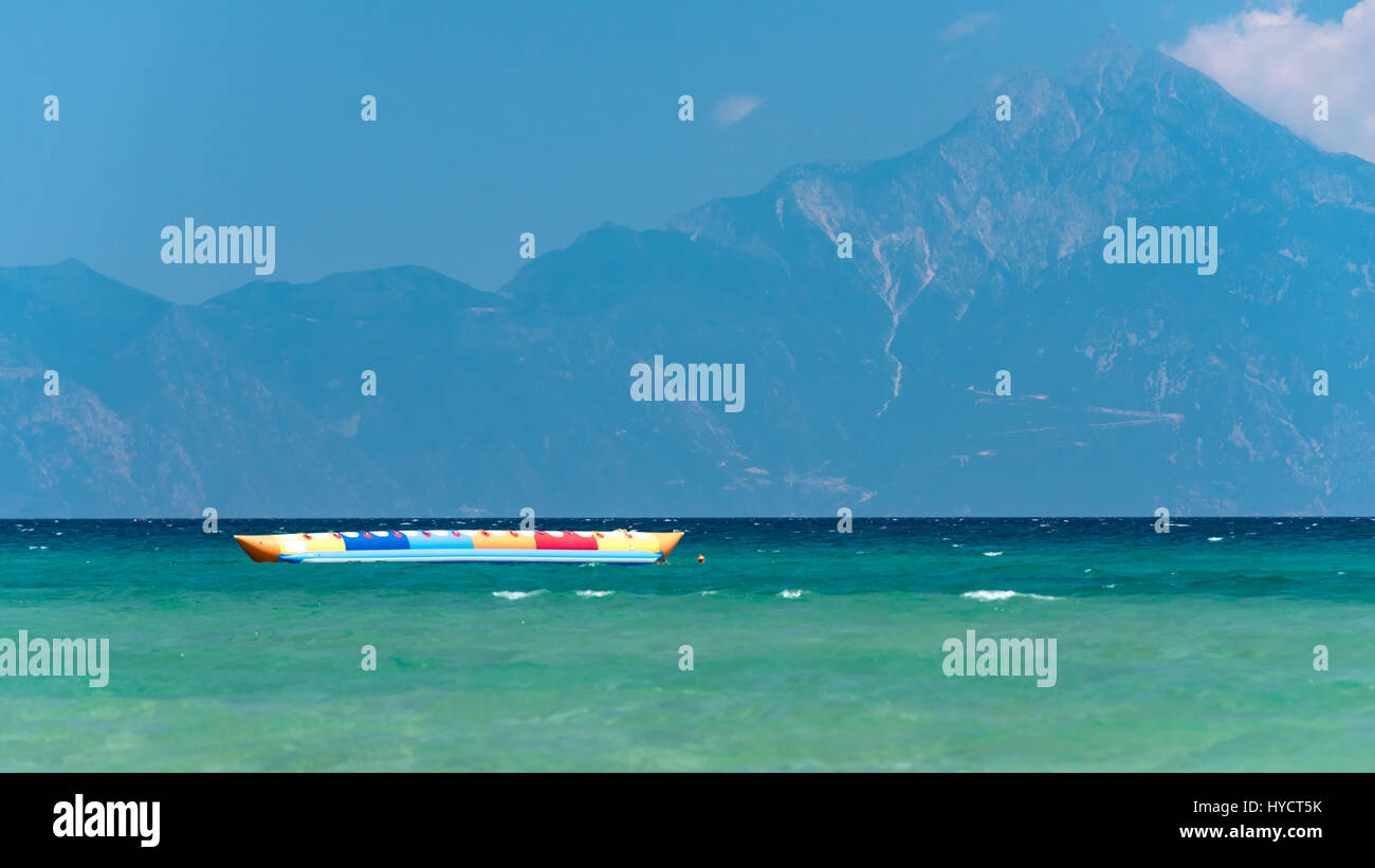 Inflatable banana shaped boat at sunset on a calm sea, Mount Athos in the background Stock Photo