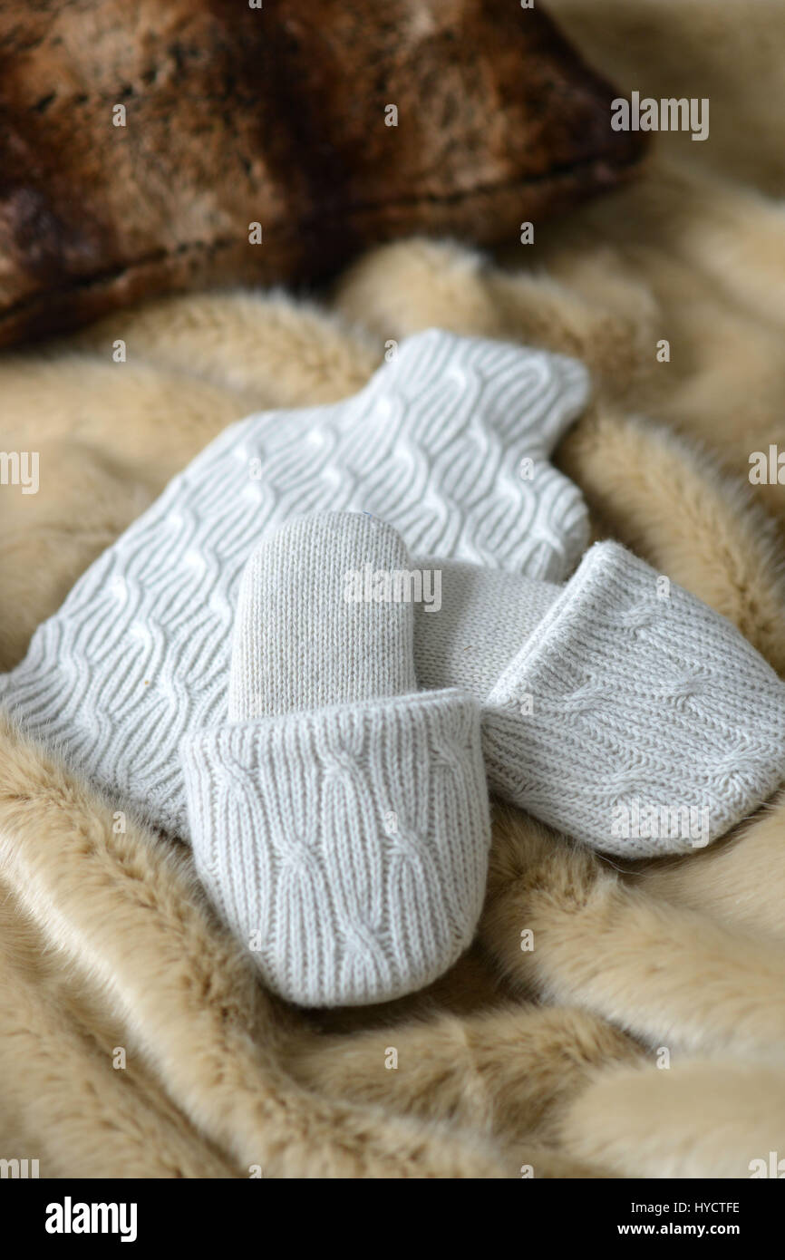Knitted slippers and water bottle on faux fur rugs Stock Photo