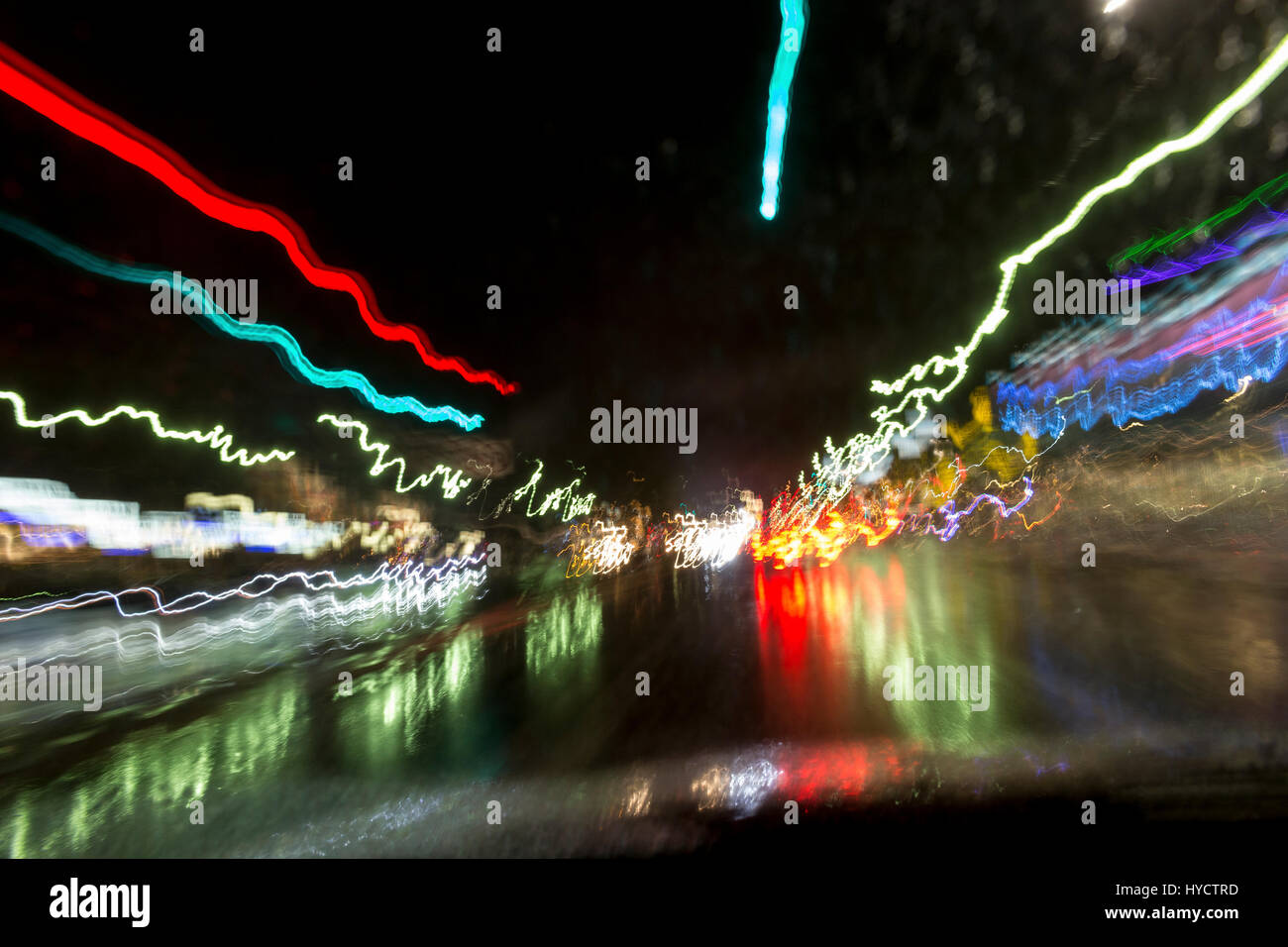 night shot of colorful car light trails with red and green reflections on wet street Stock Photo