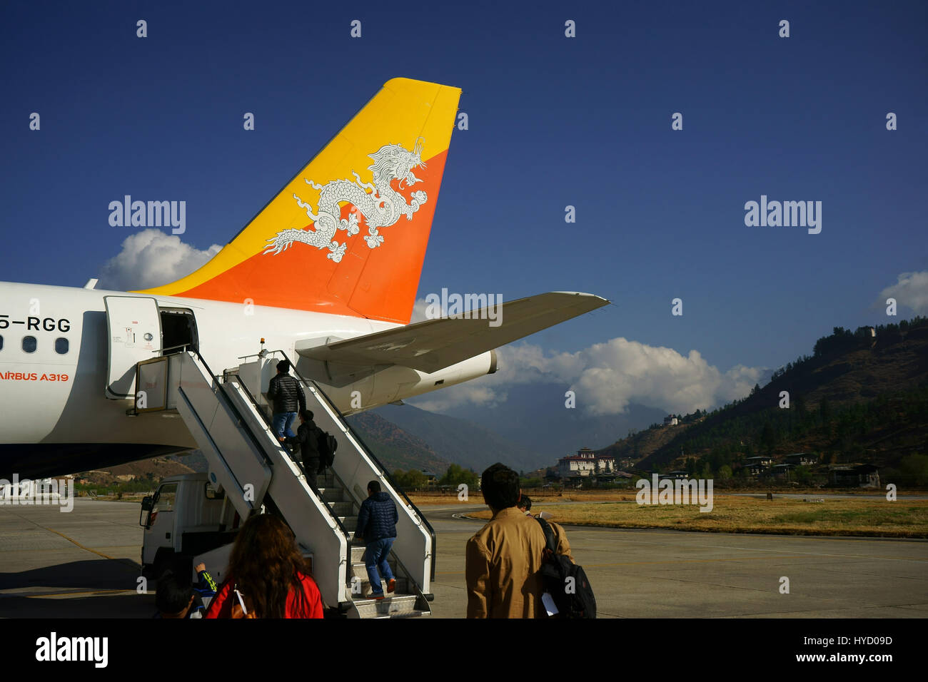 Passengers boarding Drukair Royal Bhutan Airline Airbus A319 at Paro airport with Paro Dzong castle in back, Bhutan Stock Photo