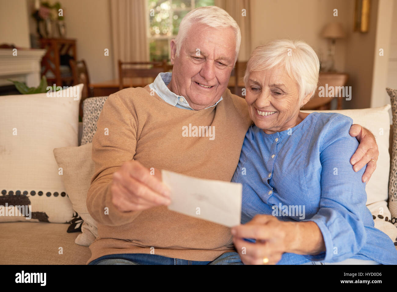 Smiling senior couple looking at old photos together at home Stock Photo
