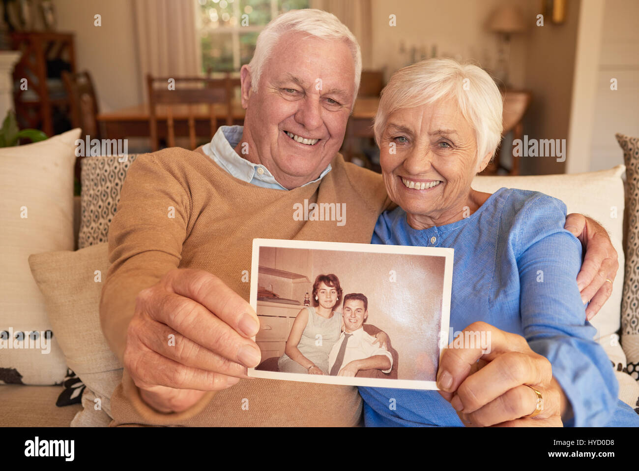 Smiling senior couple holding a photo of their youthful selves  Stock Photo
