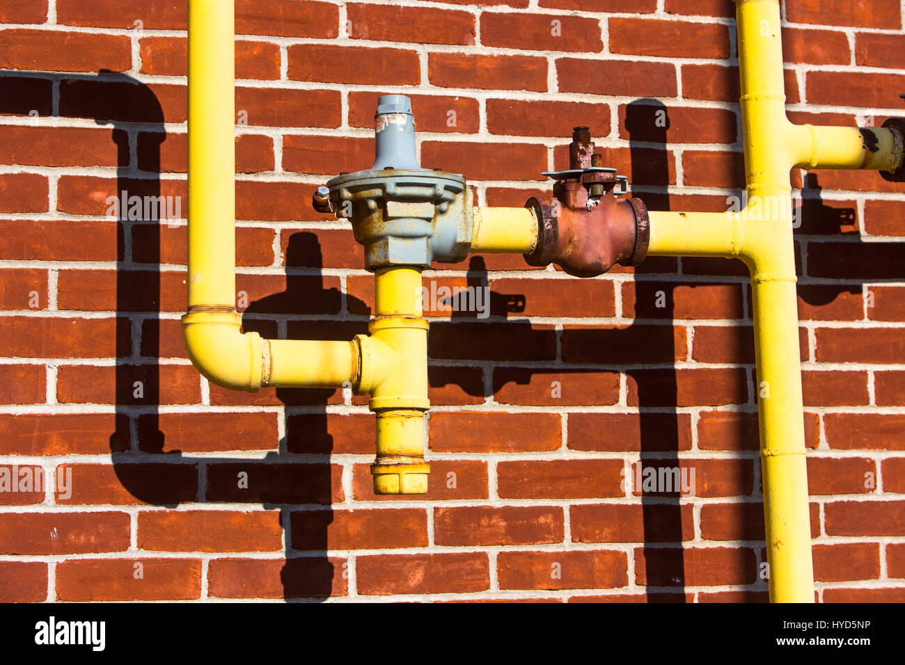 Close up of pipes in front of brick wall Stock Photo