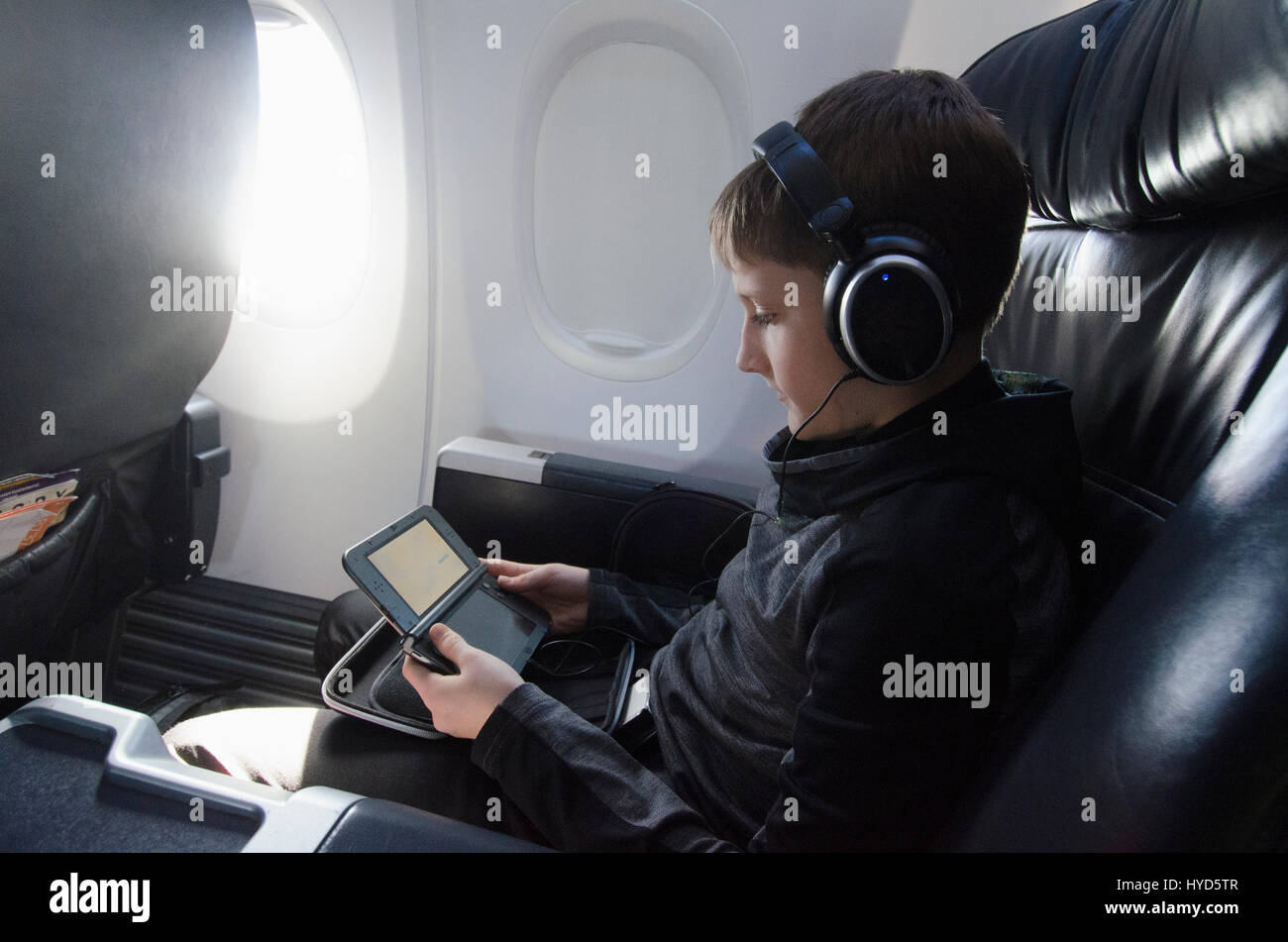 Boy sitting in plane and playing video game Stock Photo