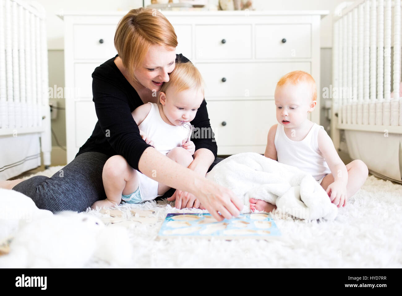Mother playing with sons (12-17 months) in nursery Stock Photo