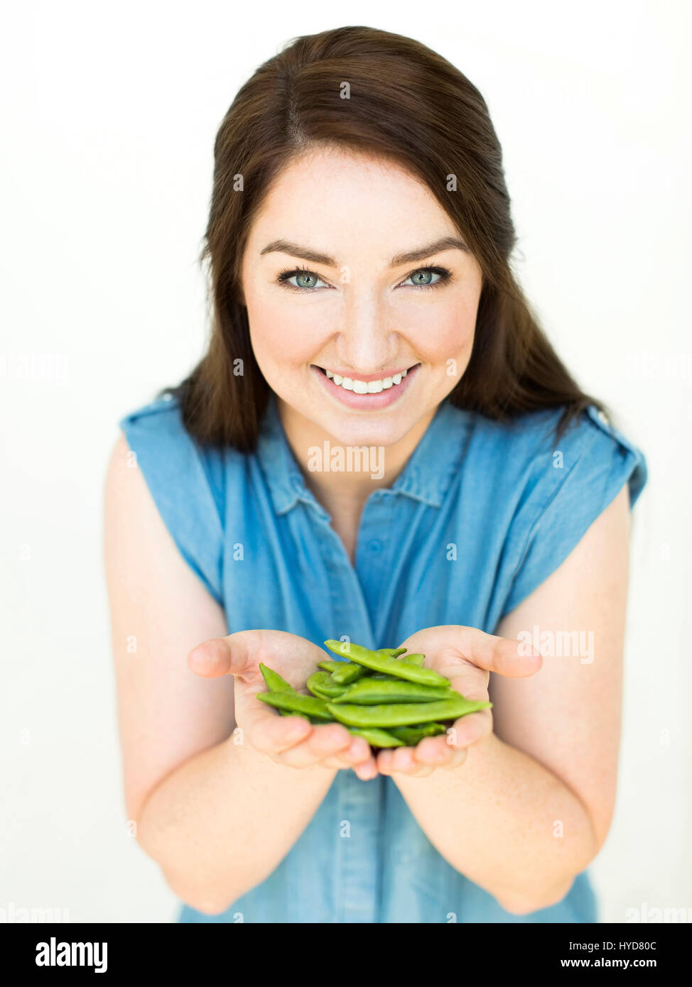 Woman wearing blue top holding sugar snap peas Stock Photo