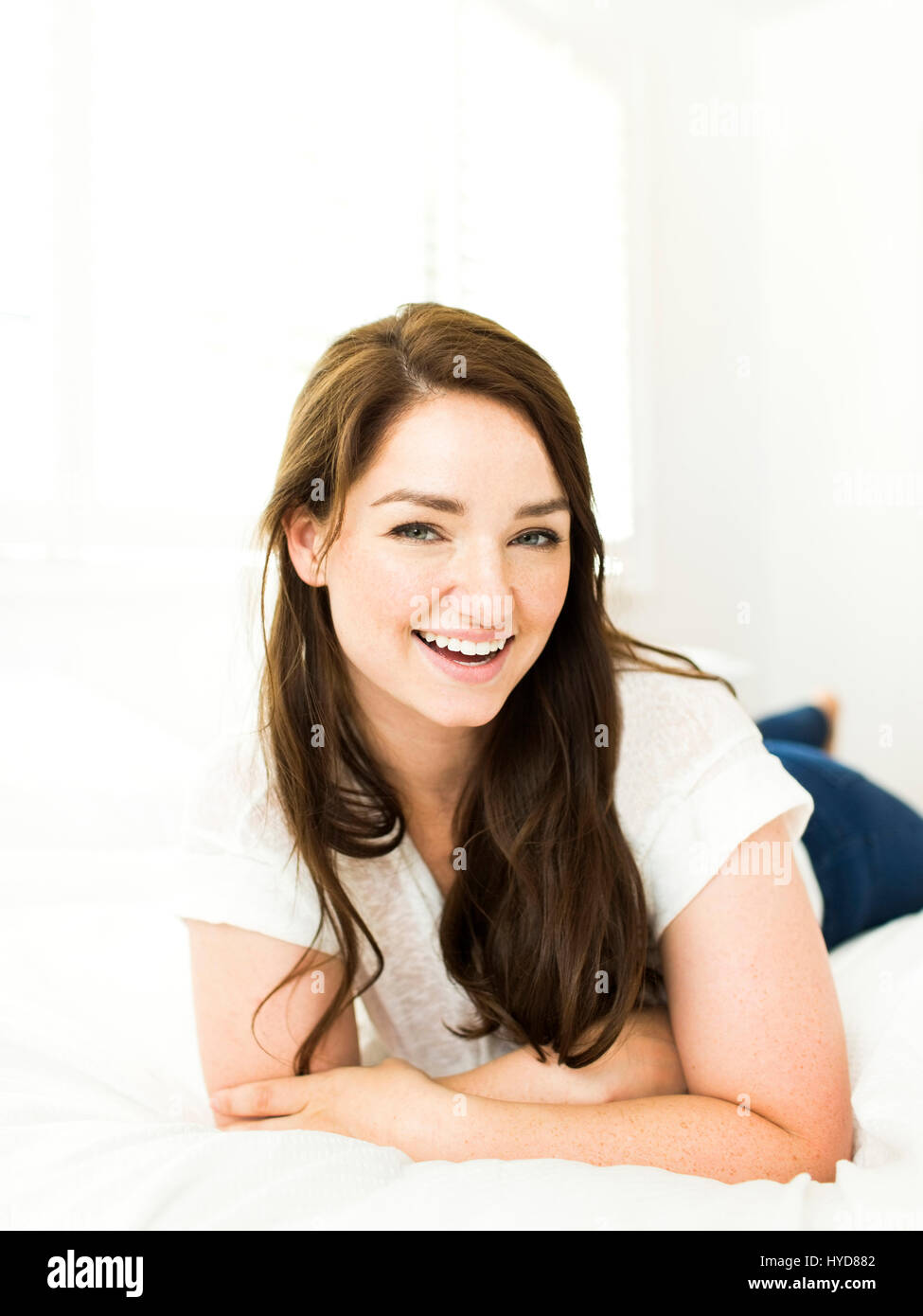 Portrait of woman lying on bed and smiling Stock Photo