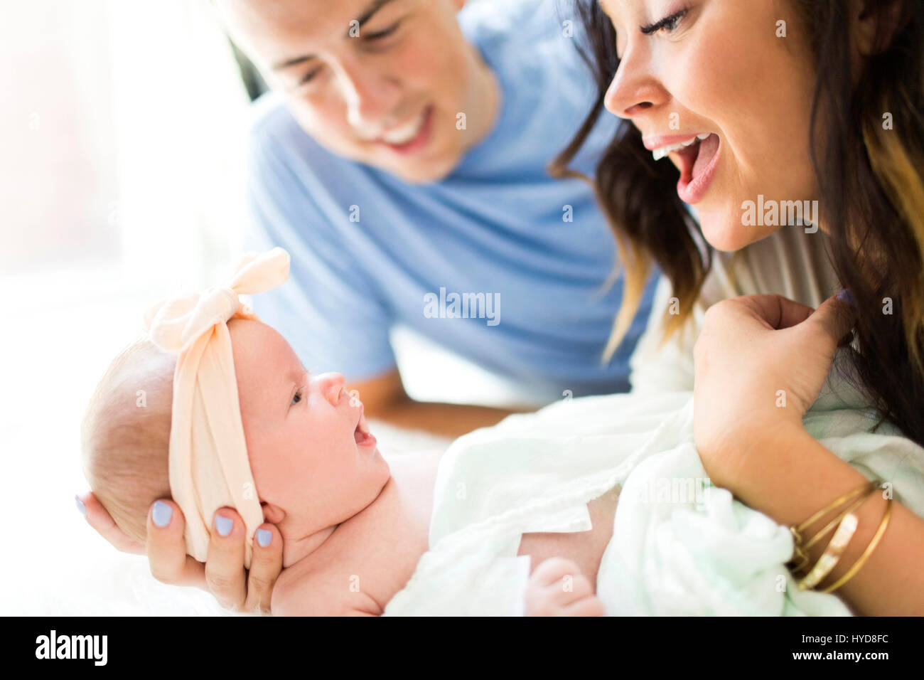 Parents lying on bed with  daughter (0-1 months) Stock Photo