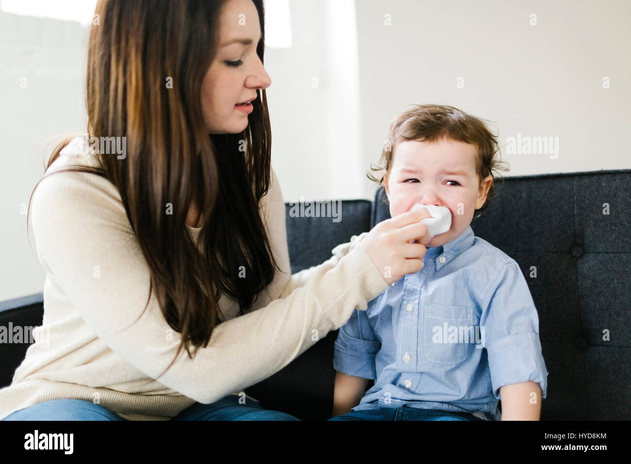 Mother helping son (4-5) blow nose Stock Photo