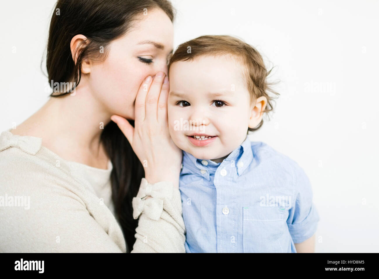 Mother whispering into son's (4-5) ear Stock Photo