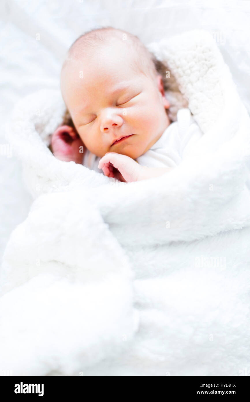 Baby boy (2-5 months) sleeping in white blanket Stock Photo