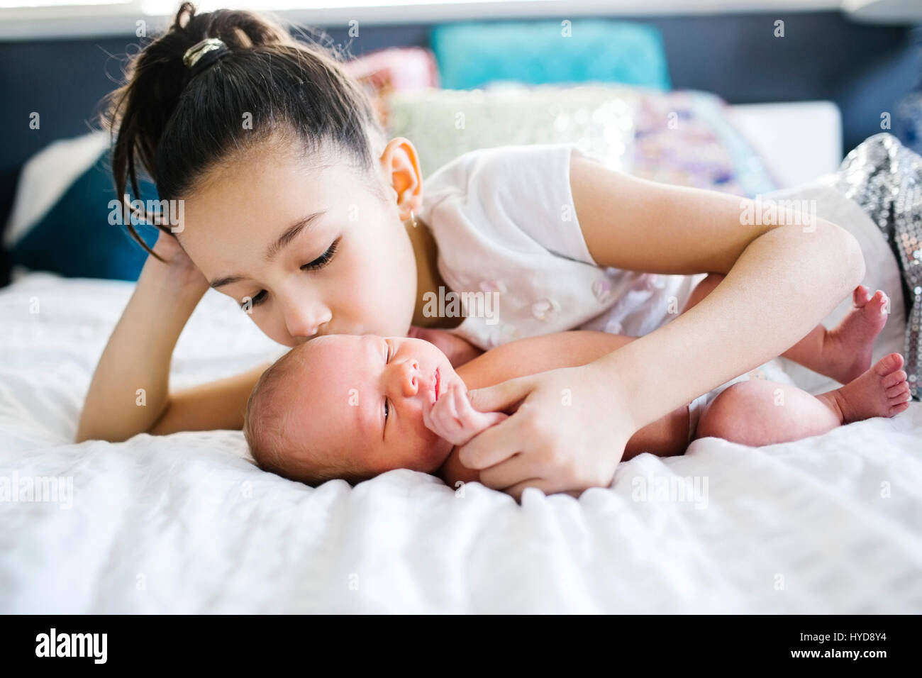 Girl (10-11) kissing brother with care (2-5 months) Stock Photo