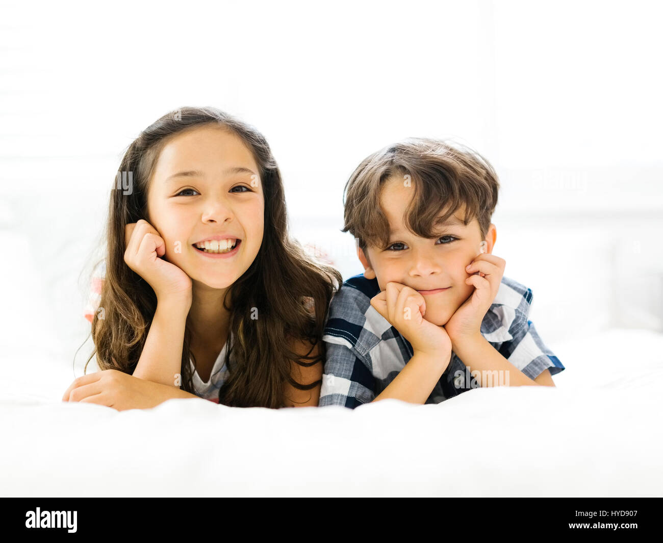 Siblings (10-11, 6-7) lying in bed side by side Stock Photo