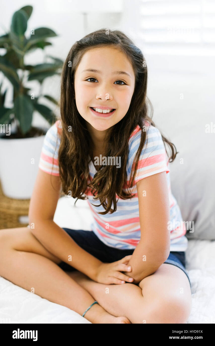 Portrait of content girl (10-11) sitting with legs crossed Stock Photo